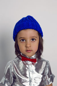 Portrait boy child in a blue knitted hat and silver shirt red bow tie on the background