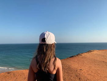 Rear view of man looking at sea against clear sky