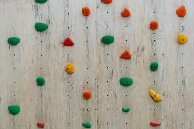 Colourful climbing holds on a wood climbing wall