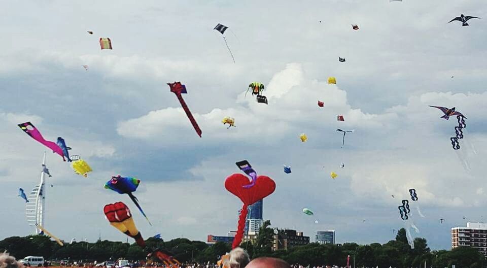 flying, sky, cloud - sky, mid-air, leisure activity, large group of people, lifestyles, low angle view, men, cloudy, fun, person, air vehicle, motion, transportation, day, enjoyment, flag, celebration