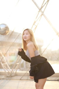 Low angle view of young woman standing against wall