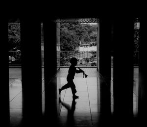 Side view of silhouette man walking on tiled floor in building