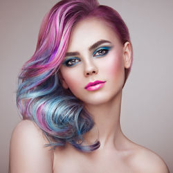 Close-up portrait of young woman against pink background