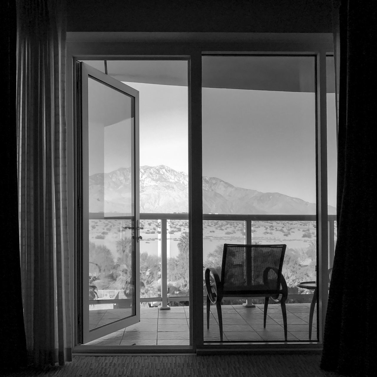 window, indoors, mountain, water, lake, glass - material, transparent, chair, mountain range, sky, day, blue, sea, scenics, window frame, tranquility, no people, tranquil scene, horizon over land