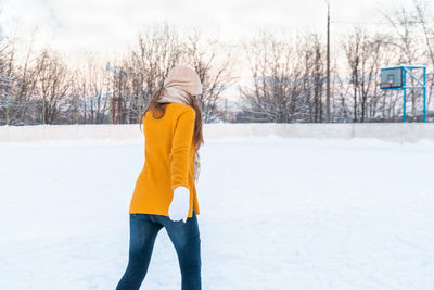 Portrait of happy young woman in yellow jacket skating at the rink