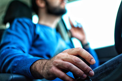 Midsection of man holding hands sitting on floor