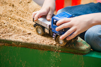 Midsection of child playing with toy truck in sand