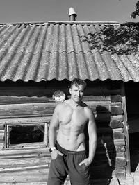 Full length of shirtless man standing against built structure