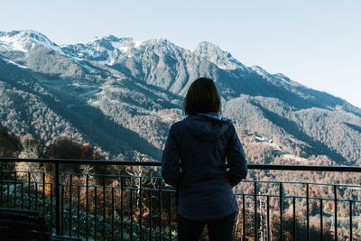 Rear view of woman standing on snowcapped mountain