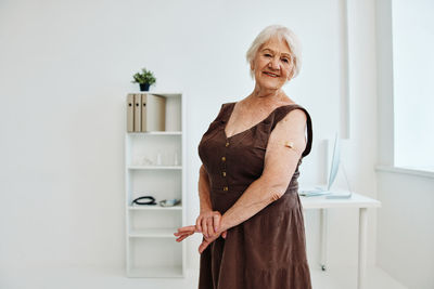 Portrait of woman standing against wall at home