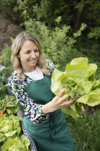 Portrait of smiling young woman standing amidst plants