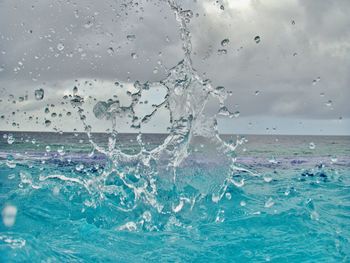 Close-up of water splashing in sea against sky
