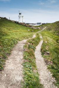 Road amidst field against sky