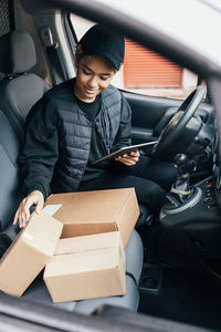 Full length of young man using phone while sitting in car