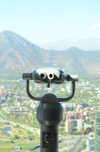 Close-up of coin-operated binoculars against cityscape