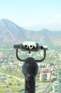 Close-up of coin-operated binoculars against cityscape