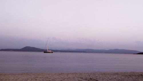 Sailboat in sea against sky during sunset