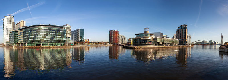 Buildings by river against sky in city