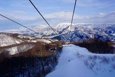 Ski lift over snowcapped mountains against sky