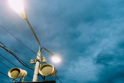 Low angle view of illuminated street light against cloudy sky