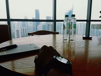 Close-up of hand on table by window