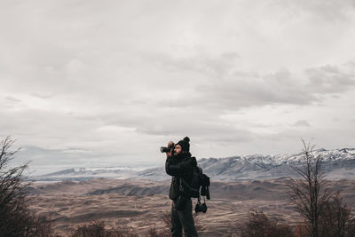 Man photographing on mountain against sky