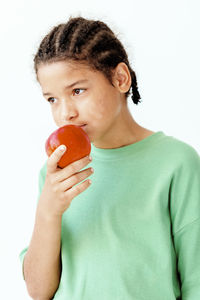 Portrait of young woman holding heart shape against white background