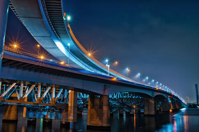 Low angle view of illuminated bridge against sky at night