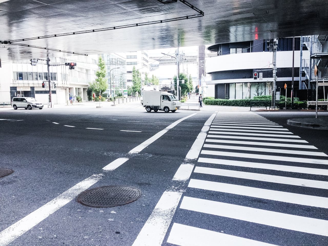 building exterior, street, architecture, road marking, city, built structure, transportation, road, car, the way forward, city street, shadow, day, sunlight, incidental people, outdoors, sidewalk, city life, building, asphalt