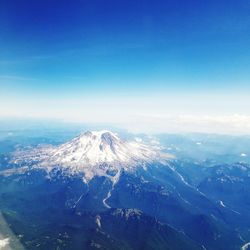 Aerial view of snowcapped mountains against blue sky