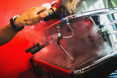 Cropped image of person working on coffee machine at cafe