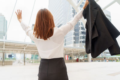 Rear view of woman with umbrella in background