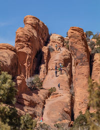 Hikers on red sandstone rock formations in stunning mountainous terrain