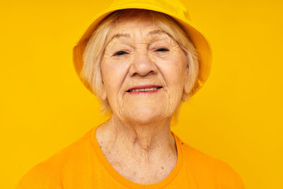 Portrait of young woman against yellow background