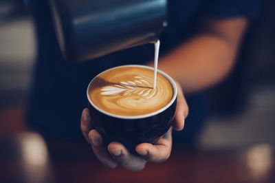 Close-up of hand holding coffee cup