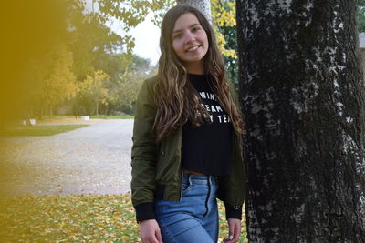 Young woman standing on tree trunk