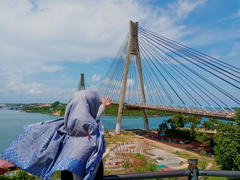 Rear view of woman standing on bridge against sky
