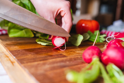 Cropped hand of man cutting vegetables on table