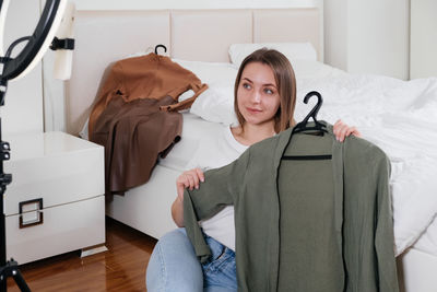 Female blogger recording vlog video on smartphone at home online influencer on near bed choosing