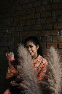 Portrait of smiling woman against brick wall