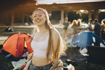Portrait of smiling young woman wearing sunglasses standing at music festival