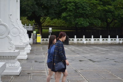 Rear view of women standing on footpath