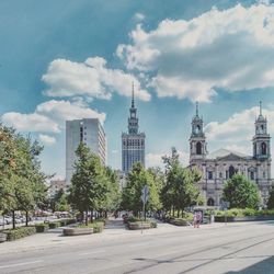 View of trees and buildings against cloudy sky