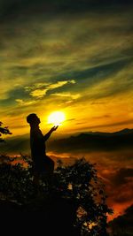 Silhouette man standing against sky during sunset