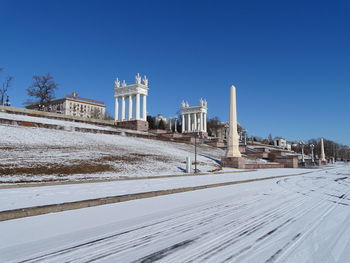 Snow covered buildings against clear blue sky