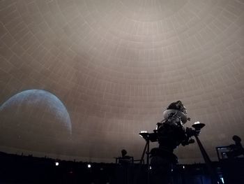 Low angle view of illuminated lighting equipment at night