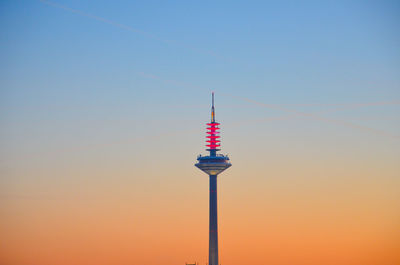 Low angle view of communications tower against sky during sunrise