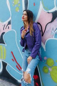 Full length of woman standing against graffiti wall