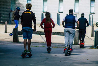 Rear view of people skateboarding on street