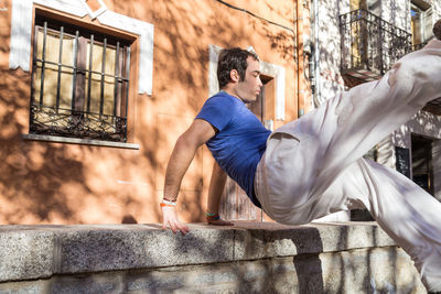 Close-up of man exercising against house